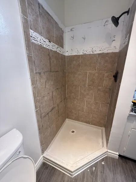 Outdated and stained shower tiles with dark moldy grout before reglazing